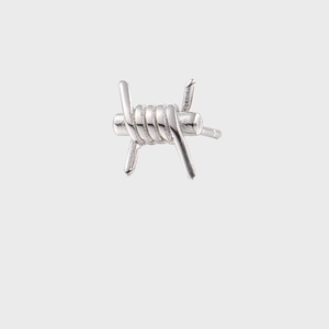 Dettaglio macro dell'orecchino a filo spinato argento in stile punk industriale