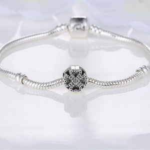 Ethnic alloy four-leaf clover hollow bead charm on a silver snake chain bracelet