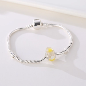 Dettaglio di un bracciale a catena serpente d'argento con perla di vetro gialla a stella