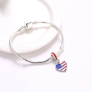 Silver snake chain bracelet with heart-shaped American flag pendant on white plate
