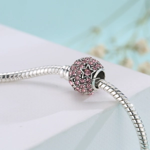 Detailed close-up of a silver snake chain bracelet with pink crystal star-shaped charm
