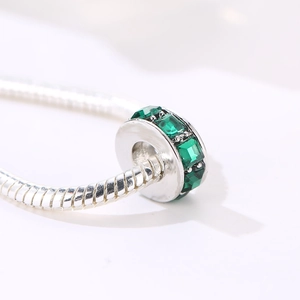 Vista macro de un abalorio de gema verde de corte cuadrado en una pulsera de cadena de plata