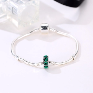 Detalle de pulsera de cadena de serpiente plateada con dije de circón verde y cierre