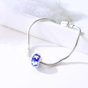 Blue glass star charm on silver snake chain bracelet over elegant white background