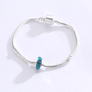 Detalle de pulsera de cadena de serpiente plateada con dije de cristal azul oscuro en blanco