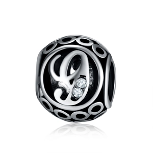Macro view of vintage silver hollow charm bead with letter engraving and cubic zirconia