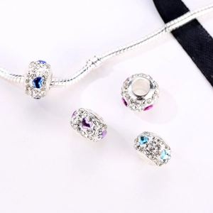 Detailopname van hartvormige strass-bedeltjes op een zilveren slangenketting