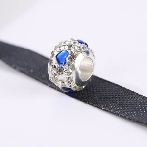 Macro-detail van zilveren bedel met witte kristallen en blauwe hartstenen op lint