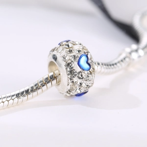 Macro-detail van de zilveren bedel met blauwe hartjes en pavé-kristallen op slangenketting