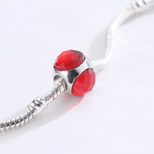 Macro di un ciondolo in argento con due cristalli rossi su catena a maglia snake