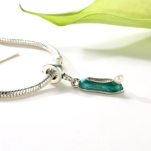 Detail of shoe-shaped charm with green enamel and pearl on a silver snake chain