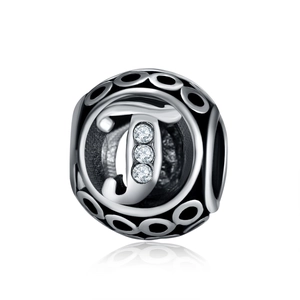 Close-up of retro hollow silver bead with letter J and sparkling zircon inlay
