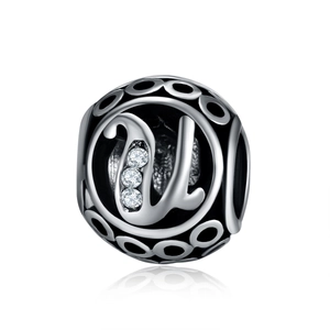 Macro detail of silver charm bead with hollow patterns and letter U featuring three zircons