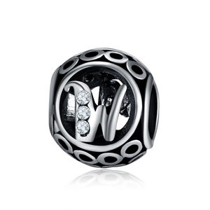 Macro view of hollow silver charm bead with letter W and sparkling zircon inlay