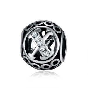 Macro shot of silver hollow bead charm with letter X and sparkling zircon stones