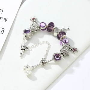 Detail of purple crystal beads and silver crown charms on a snake chain bracelet