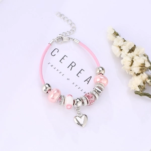 Pink cord bracelet with silver heart charm and crystal beads on minimalist white background