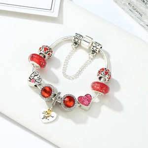 Detailed macro view of silver charm bracelet featuring red crystal beads and love you heart pendant