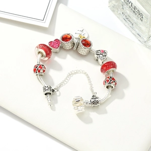 Detailed macro of a silver snake chain bracelet with red crystal beads and I love you pendant