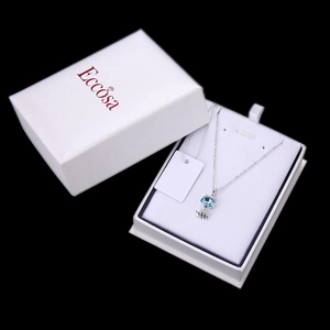 Detalle de collar de espina de pescado con cristal azul en una caja de regalo blanca