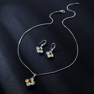 Macro detail of amber crystal butterfly pendant and earrings on black silk background