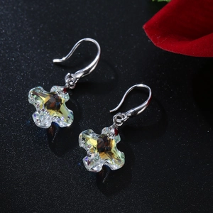 Elegant silver-toned cross star crystal drop earrings on a dark textured surface