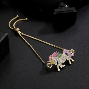Detail of adjustable gold unicorn bracelet with colorful sparkling crystals on black background
