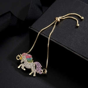 Macro shot of colorful zircon unicorn charm on a golden adjustable box chain bracelet