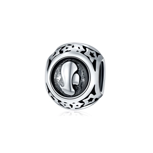 Macro detail of silver charm bead with relief profile and star cut-out patterns