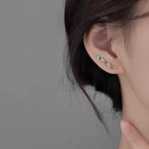 Close-up of colorful zircon climber earrings on model ear with silver metal finish