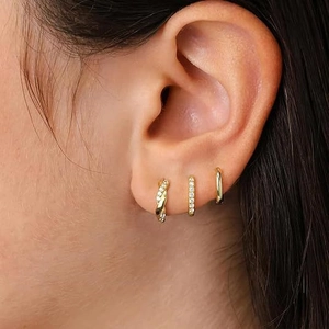 Close-up of a three-piece gold earring set with zircon studs and a twisted hoop design