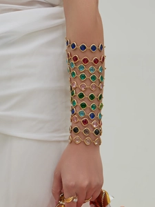 Detail of colorful geometric faceted glass stone bracelets with gold metal claw setting