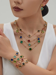 Detailed close-up of layered necklace and bracelet with colorful faceted gemstones