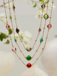 Detailed close-up of gold chain necklaces with colorful faceted glass stones in various shapes