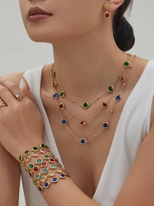 Detail of bohemian jewelry set featuring multi-layered necklaces and faceted gemstone rings