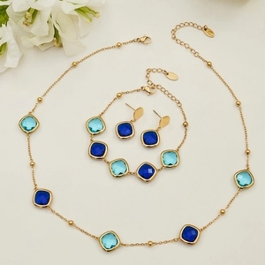 Geometric stainless steel jewelry set with blue faceted glass stones on white background