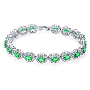 Macro detail of silver tennis bracelet with oval green emerald-cut stones and zircon halo