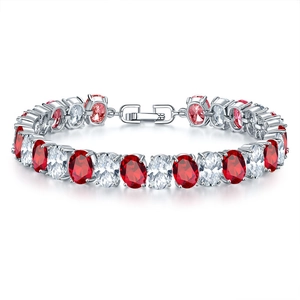 Macro detail of silver tennis bracelet with oval red and clear stones in four-prong setting