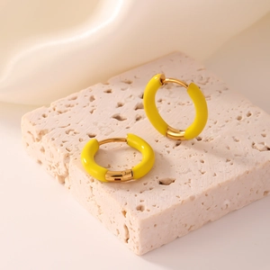 Detail view of vibrant yellow enamel hoop earrings on a textured stone display pedestal