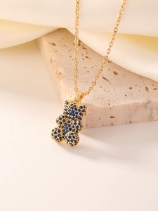 Macro shot of gold necklace with bear pendant featuring dark blue heart-shaped cubic zirconia