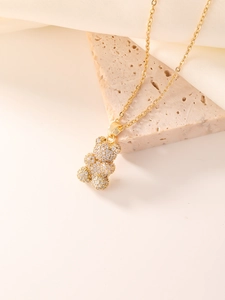 Close-up of a sparkling gold bear pendant necklace with zircon on a marble base