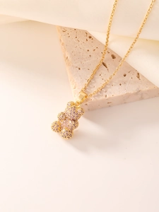 Detailed view of a gold teddy bear pendant set with pink zircons on a marble background