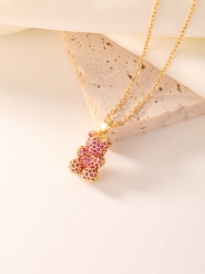 Macro detail of a teddy bear pendant encrusted with pink cubic zirconia on a gold chain