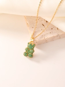 Close-up of golden bear pendant necklace with sparkling green zircon inlays