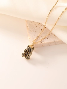 Macro detail of a golden bear pendant with black pavé zircon stones on a beige stone surface