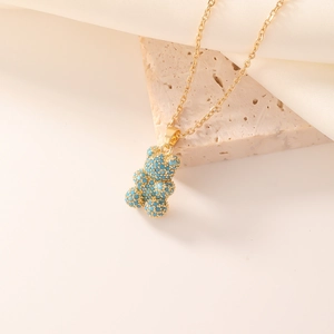 Chic gold link necklace with a turquoise-beaded 3D bear pendant on beige stone