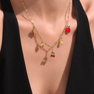 Collar de cadena dorada con dijes de cereza y piña lucido por una modelo