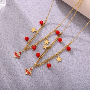 Close-up of gold necklaces with red faceted beads and Christmas tree pendants