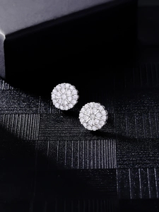 Macro shot of silver hip hop stud earrings with pave cubic zirconia cluster on black velvet