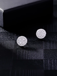 Macro close-up of round hip-hop stud earrings with micro-pave cubic zirconia on black surface